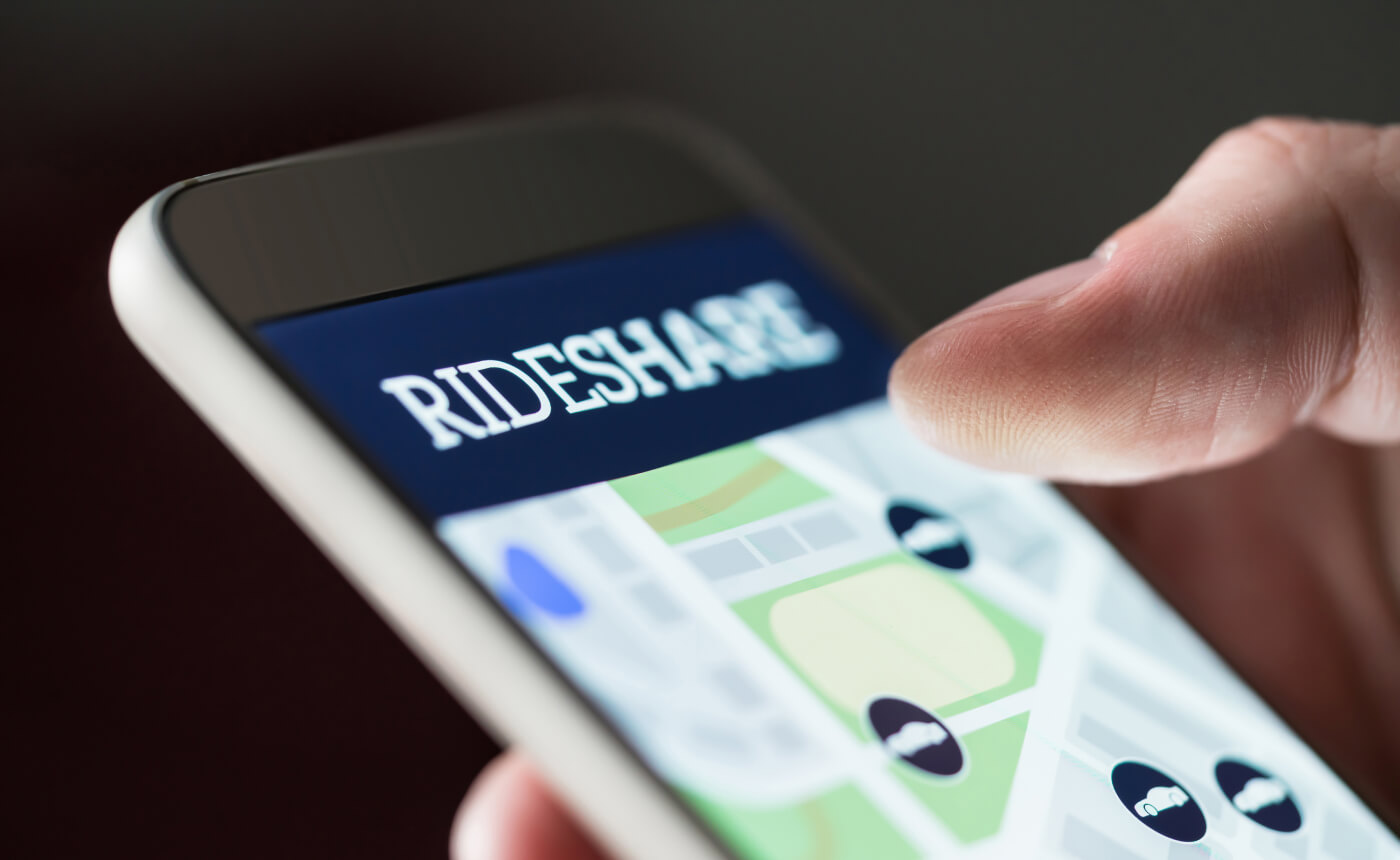 A smartphone screen shows a rideshare app, featuring a map with circular icons. A hand hovers as the user decides on an option to select, utilizing intuitive features that enhance navigation.