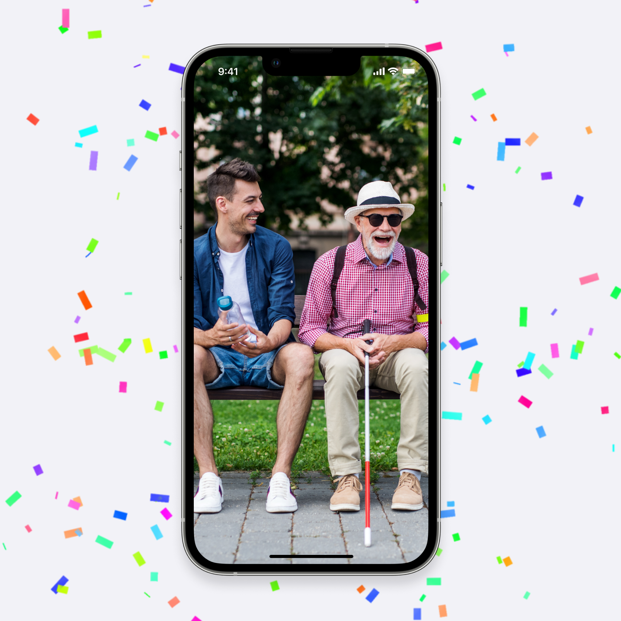 A smartphone showcases a joyful photo of two men, one older with a hat and cane, sharing laughter on a bench. Bright confetti adds a festive touch around the phone.