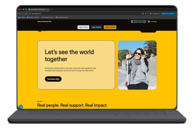 A laptop screen displays a website with a yellow background, featuring text about connecting blind and low vision users with volunteers, highlighting color contrast for low vision, and a photo of a smiling woman using a white cane.
