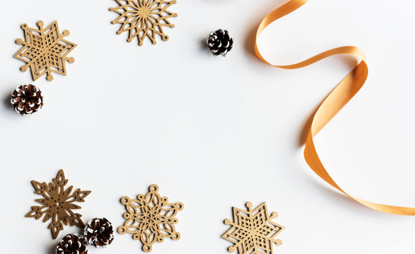 Wooden snowflakes, pine cones, and a shimmering gold ribbon are artfully arranged on a pristine white background, creating an elegant and festive display.