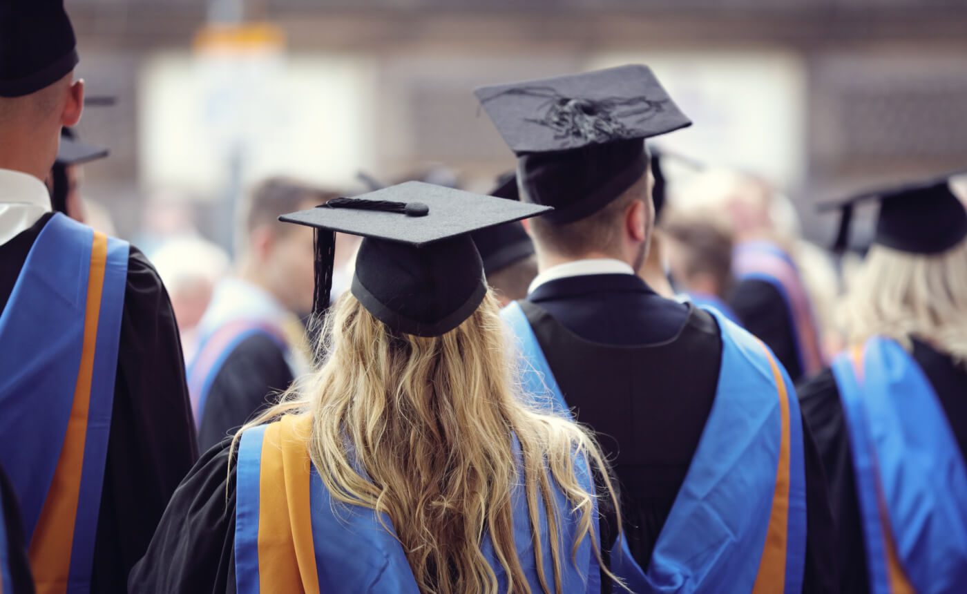 A group of graduates in caps and gowns stand proudly outdoors, looking towards a bright future.