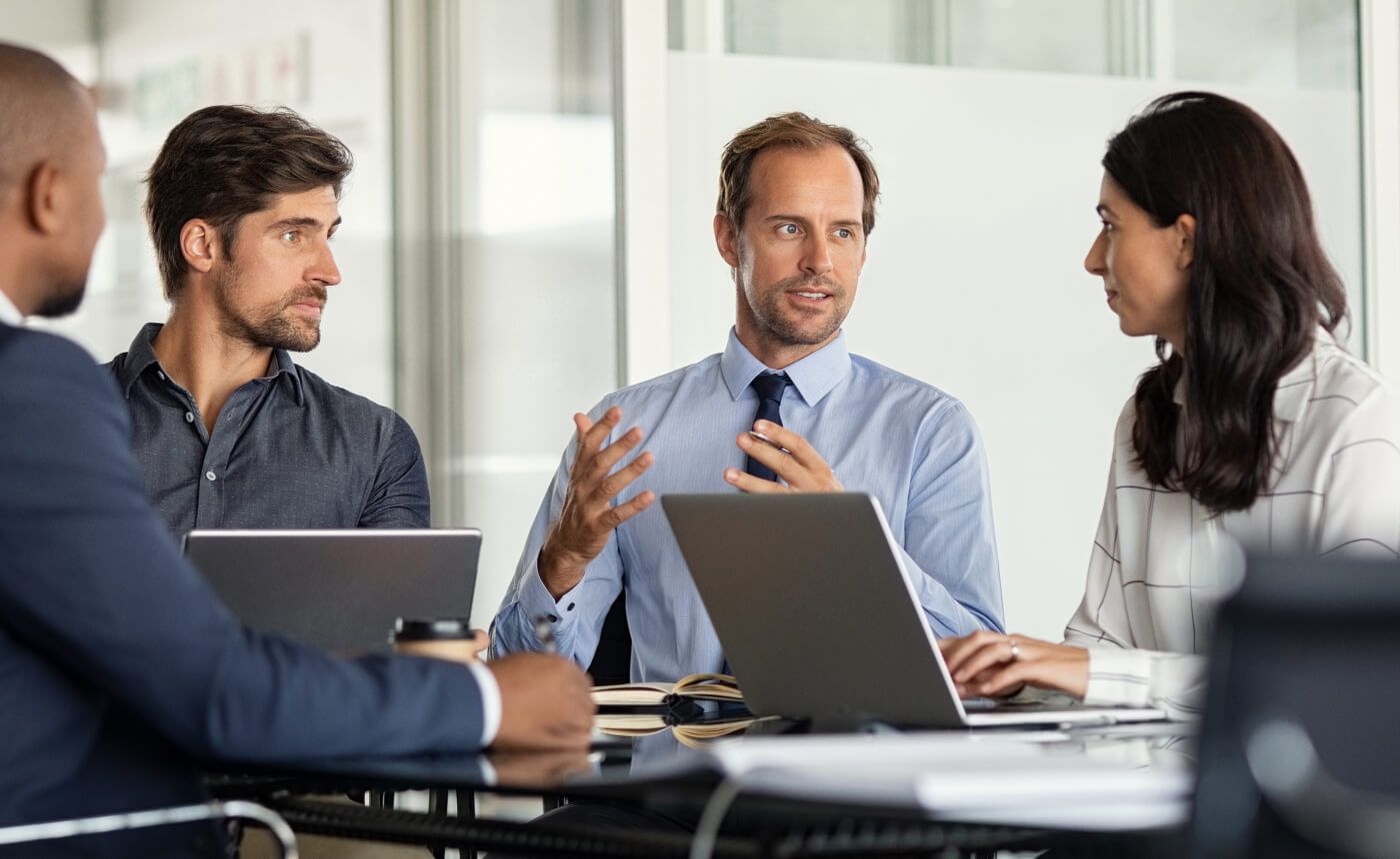 Four colleagues collaborated in a brainstorming session, surrounded by laptops, documents, and innovative ideas.
