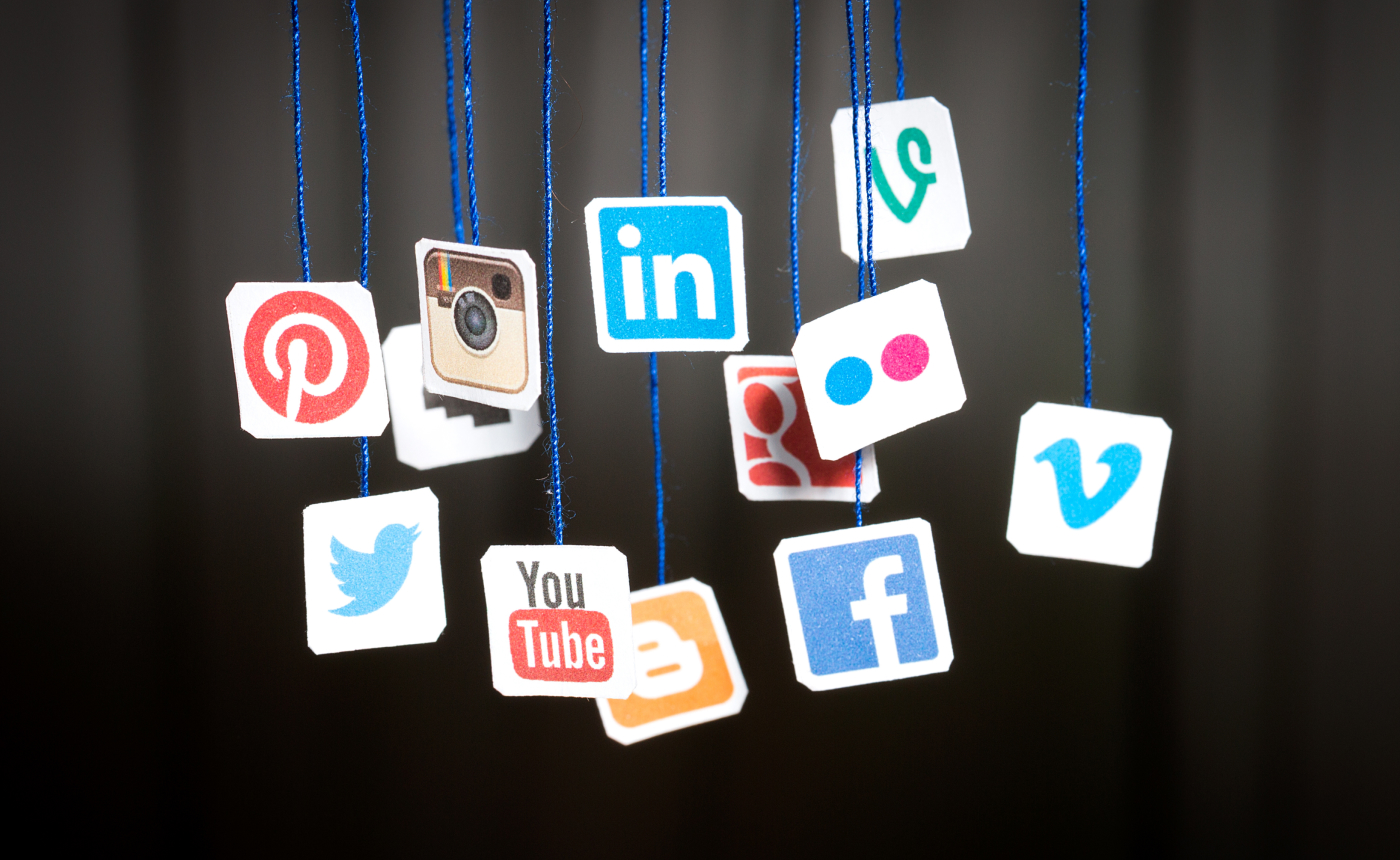 Floating social media logo icons, such as Pinterest, Instagram, LinkedIn, WhatsApp, and more, subtly illuminate a dark background.