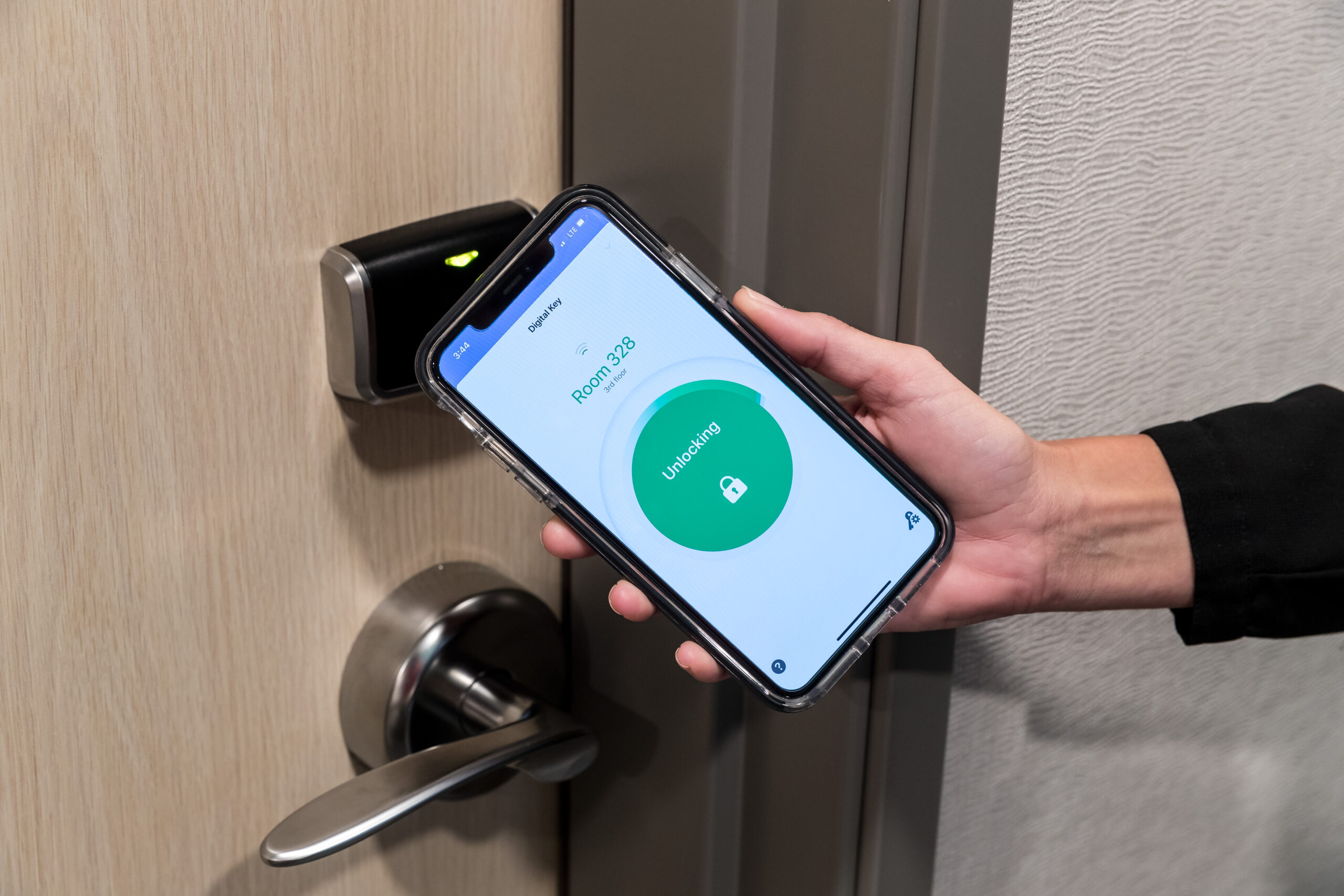 Using an innovative smartphone app, a person effortlessly holds their phone near the digital lock to unlock their hotel room door. This seamless technology ensures a smooth and efficient entry experience for guests.