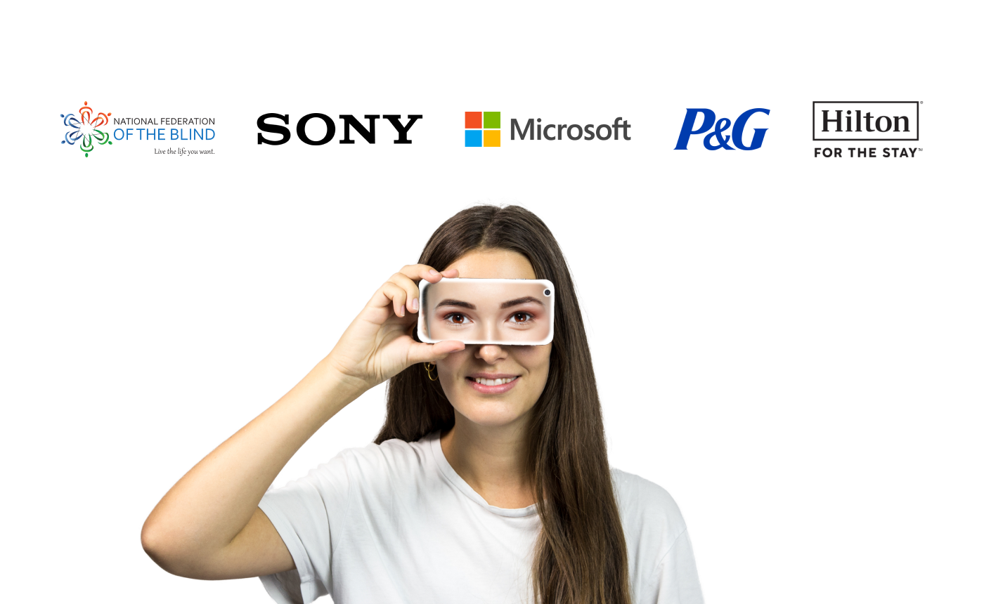 A woman in a white shirt holds a sleek white device over her right eye. Above her, logos of the National Federation of the Blind, Sony, Microsoft, P&G, and Hilton are prominently displayed.