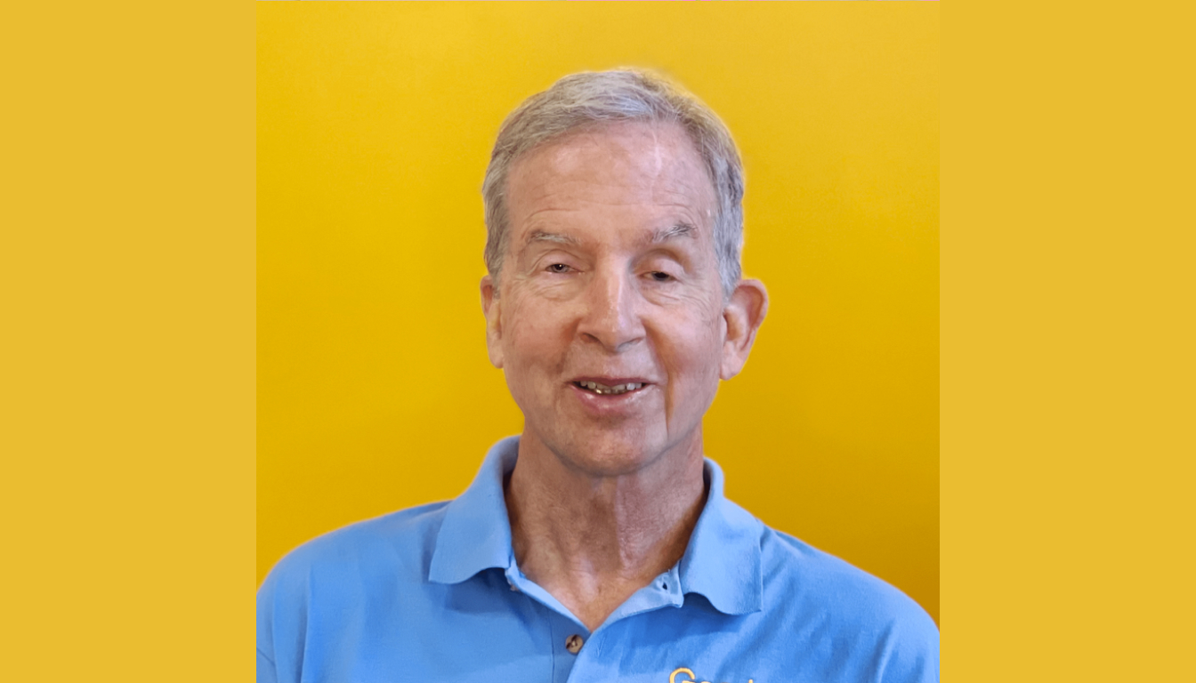 An older man, exuding confidence in a blue polo shirt, stands against a cheerful yellow background.